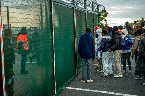 Des migrants tentant de franchir les grilles du site d'Eurotunnel, fui