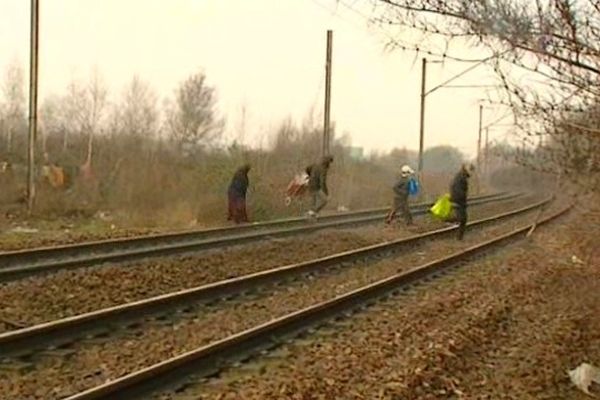 Des personnes vivant dans le camp de Roms de Lille-Sud traversent la voie ferrée, située à proximité, ce vendredi. 