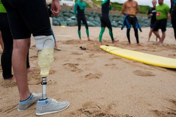 Les blessés s’initient à l’activité handisurf. Ils réalisent des exercices d'échauffement avant l'entrée dans l'eau