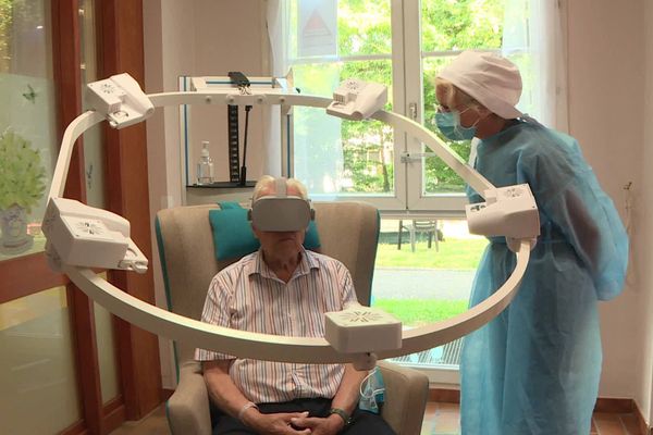 Un résident de l'Ehpad Jeanne d'Arc de Soissons teste la capsule multisensorielle sous l’œil de l'animatrice de l'établissement