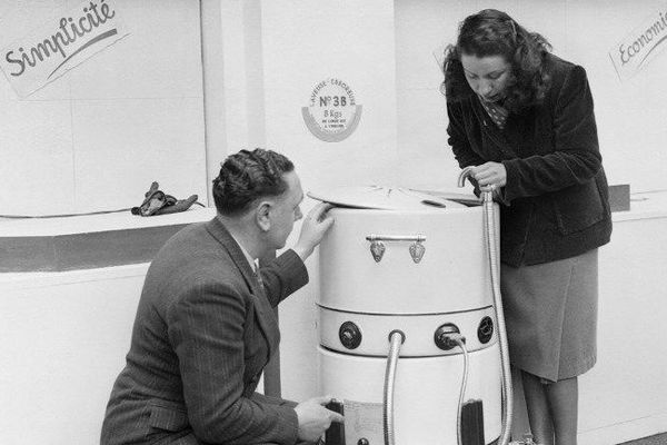 Foire de Paris : Photo prise en février 1948 d'un vendeur présentant l'une des premières machines à laver, dans le cadre de la Foire aux arts ménagers à Paris.
