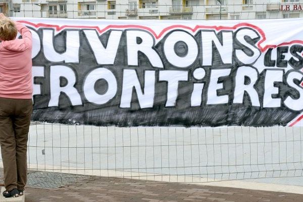 Une Calaisienne accrochant ce samedi une banderole dans sa ville pour soutenir les migrants.