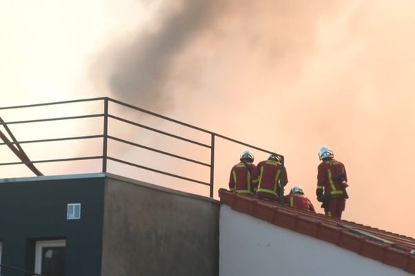 Des pompiers en intervention sur un toit pour éteindre un feu (illustration)