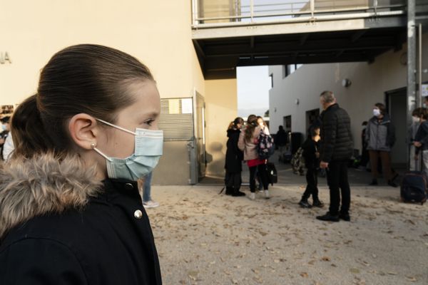 Élève masquée devant une école primaire. 