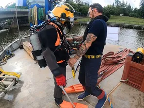 (à droite) Thierry Prod'homme prépare un scaphandrier avant la plongée.