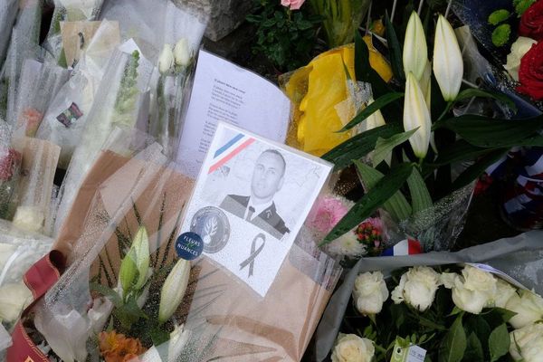 Une image du Lieutenant-Colonel Arnaud Beltrame attachée à un bouquet de fleurs déposé devant la gendarmerie de Carcassonne - 25/03/2018