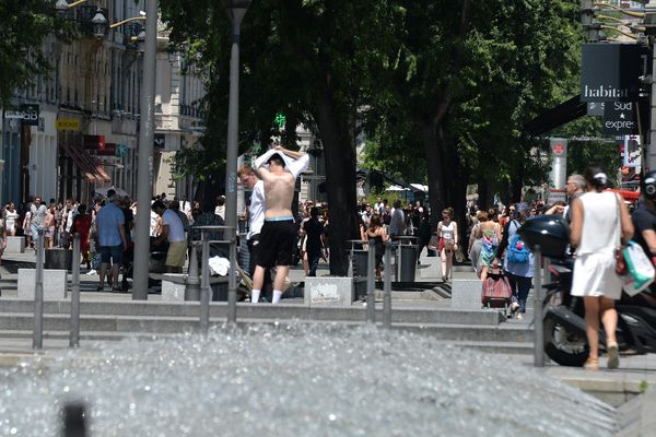 Illustration de la canicule à Lyon le 30 juin 2018 -Un jeune homme est torse nu près du jet d'eau rue de la république