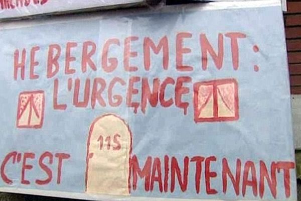 Une trentaine de personnes s'est rassemblée devant un bâtiment ayant des logements vides.