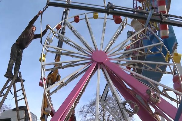 Un forain est en train d'installer son attraction au coeur de la foire du Trône