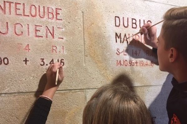 A l'intérieur de l''Ossuaire de Douaumont, ces collégiens repeignent au pinceau les noms des poilus tombés au combat. 