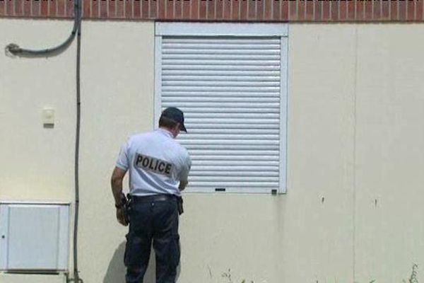 Un policier vérifie que le volet de cette maison est bien fermé et qu'il n'a pas été forcé.