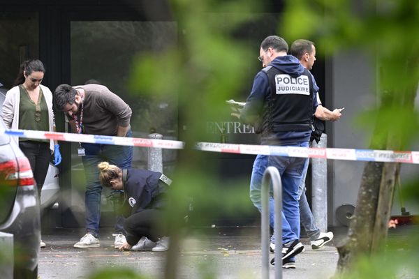 Des policiers effectuent des prélèvements sur place. Des impacts de balles sont visibles sur une porte vitrée donnant accès à la vaste salle de réception.