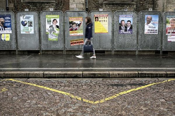 Une passante longe les panneaux d'affichage des candidats aux régionales à Dijon. Photo d'illustration. 