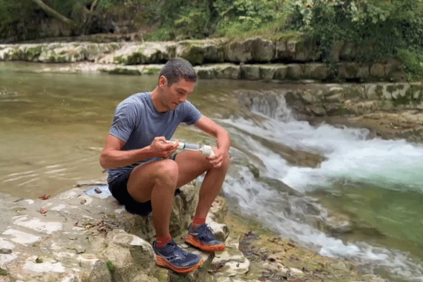 Alban Planchat, climatologue prélève l'eau d'un lac pour une étude scientifique.