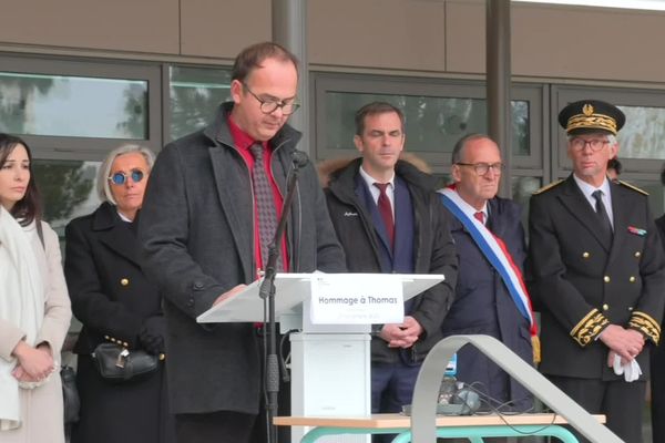 Le proviseur du lycée Dauphiné de Romans-sur-Isère rend hommage à Thomas, décédé le 18 novembre. Derrière lui, le porte-parole du gouvernement Olivier Véran assiste à la cérémonie, accompagné d'Alexandra Louis, déléguée interministérielle à l'aide aux victimes.