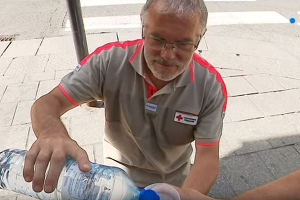 Des bénévoles de la Croix-Rouge servent un verre d'eau fraîche à un sans-abri à Pontarlier, le 25 juillet 2019.