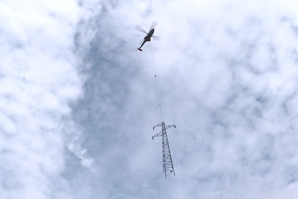 Un hélicoptère est utilisé sur ce chantier de remplacement de pylônes électriques.