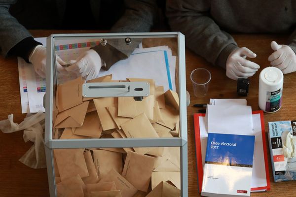 Des assesseurs portant des gants lors du premier tour des élections municipales le 28 mars 2020.