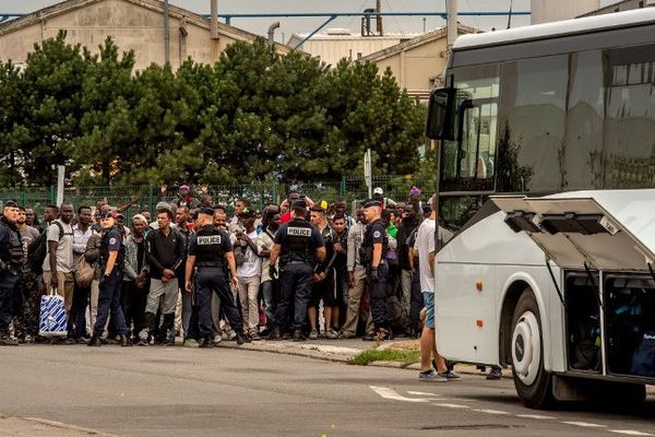 Archive : des migrants de Calais attendent avant de monter dans un bus, direction un centre d'accueil et d'orientation.