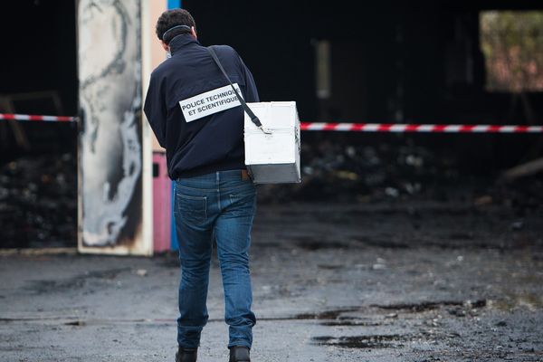 Un technicien de la police scientifique chargé de déterminer les causes de l'incendie qui a ravagé l'entrepôt