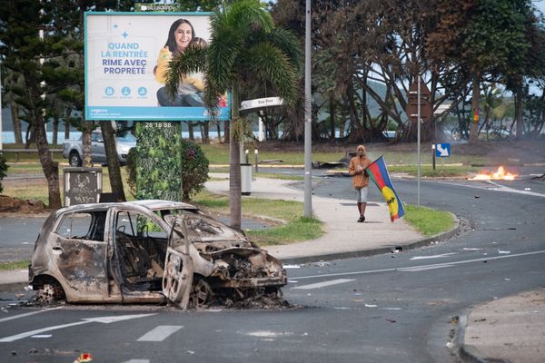 Un homme tient un drapeau du Front de libération nationale kanak et socialiste (FLNKS), le 14 mai 2024 dans les rues de Nouméa.