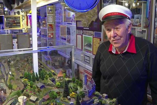 André, avec sa casquette, prend la pose pose devant l'une de ses maquettes