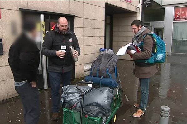 Deux bénévoles de l'Asar distribuent boisson chaude et nourriture à un homme sans abris à Rouen (Seine-Maritime).