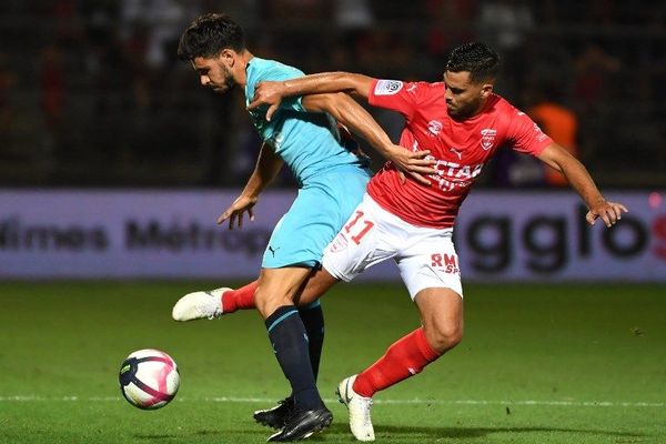 En bleu le milieu de terrain de l'OM, Morgan Sanson aux prises avec son adversaire nîmois Teji Savanier