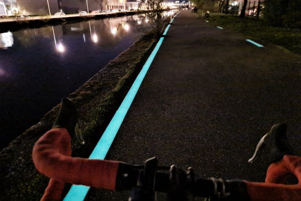 Une peinture phosphorescente limite une portion d'une bande cyclable le long d'un canal à Nancy.