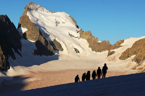 Un groupe d'alpinistes le 25 août 2023 devant la barre des Ecrins (4102 m) et le dôme de neige des Ecrins (4015 m), dont la voie normale est très affectée par le changement climatique.