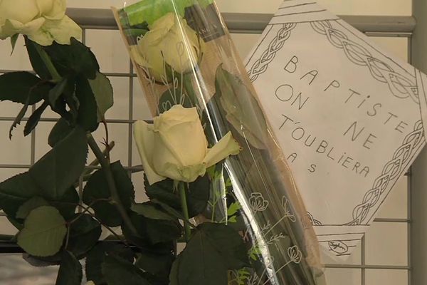 Sous un grand chapiteau blanc, devant l'établissement scolaire, des fleurs et des mots, en hommage à Baptiste