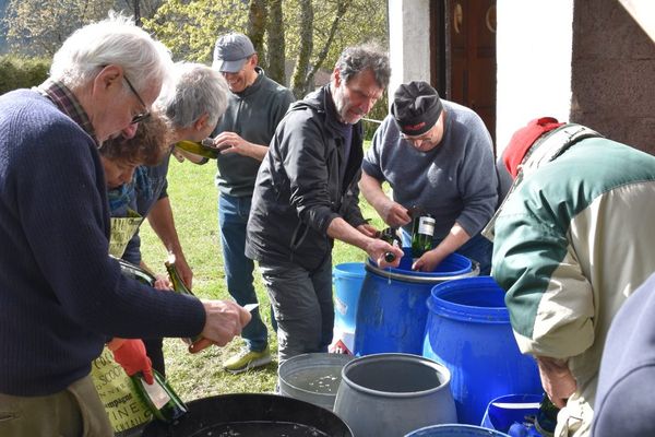 Des bouteilles collectées au cours de l’année sont rincées et débarrassées de leurs étiquettes avant d'être remplies de lessive à la cendre.