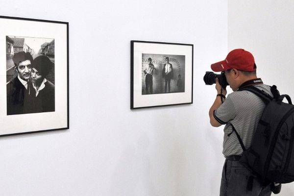 Un visiteur photographie des clichés de l'exposition de Joseph Koudelka intitulée Gitans, présent également en 2012.