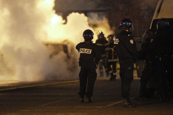 La police sécurise les pompiers qui interviennent sur une voiture en feu dans le quartier de Cronenbourg à Strasbourg le soir du réveillon.