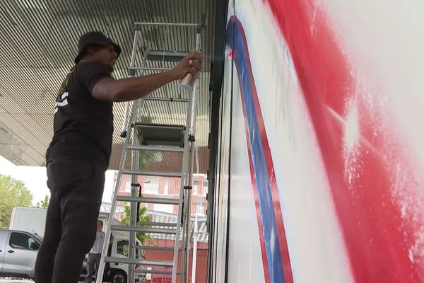 L'artiste Baron en train de réaliser sa fresque sur la façade de la mairie