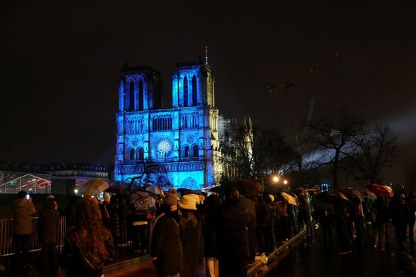 La foule se tient devant la Cathédrale Notre-Dame, illuminée à l'occasion de la réouverture officielle de l'édifice. Une cinquantaine de chefs d'Etat, de gouvernements et d'officiels ont assisté à la cérémonie à l'intérieur de la cathédrale.