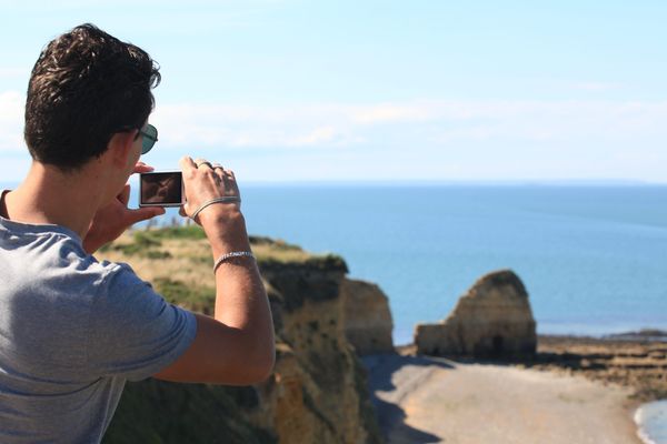 Un touriste prend en photo la Pointe du Hoc, située entre les plages de Utah Beach et Omaha Beach. 