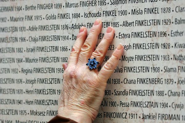 Une main touchant le Mur des Noms sur le mémorial de la Shoah à Paris.