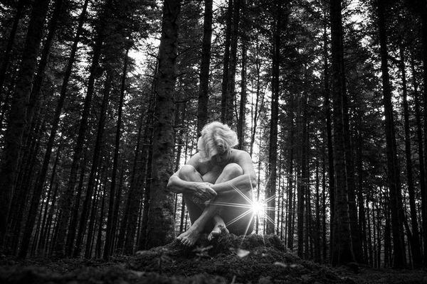 Claire Guillon, comédienne, 75 ans, pose au milieu des arbres au lever du jour près d'Orgelet dans le Jura.