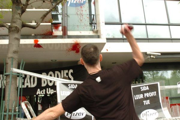 Un militant de l'association Act Up Paris lance des préservatifs de faux sang sur la façade du siège social du groupe pharmaceutique Pfizer France, le 26 avril 2005 à Montrouge.