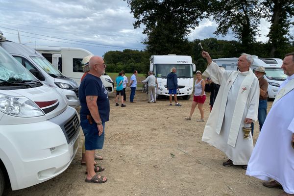 Ces deux campings-caristes reçoivent la bénédiction devant leur camping-car.