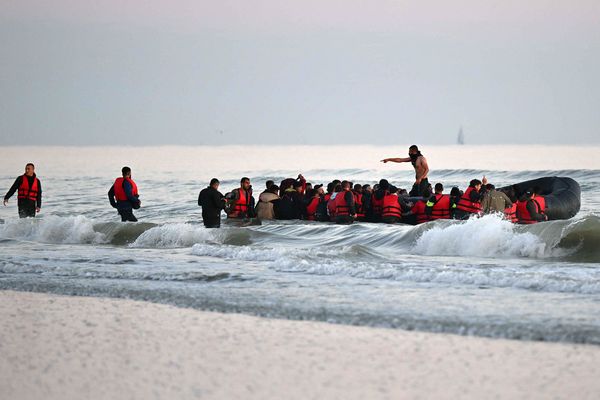 Au large de Gravelines (Nord), un passeur debout dans une embarcation de fortune au milieu de 40 migrants qui s'apprêtent à tenter la traversée pour rejoindre l'Angleterre, le 11 juillet 2022.