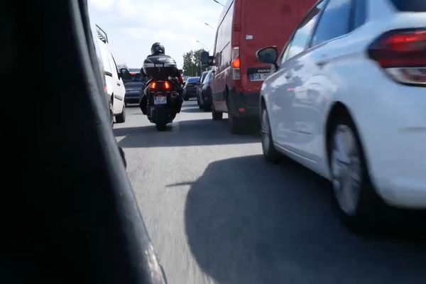 Une moto circule entre les voitures sur le périphérique