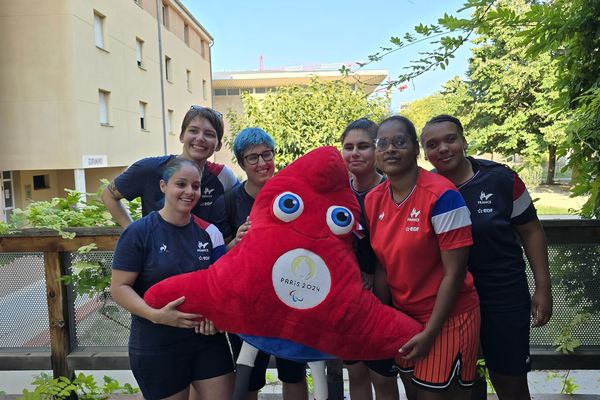 Gwendoline Matos (à gauche) entourée de ses coéquipières de l'équipe de France féminine de goalball, avec l'emblème des Jeux paralympiques 2024.