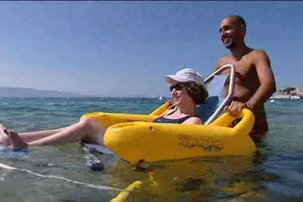 Sur la plage du Trottel, à Ajaccio, un handiplagiste accompagne une personne handicapée lors de sa baignade en mer