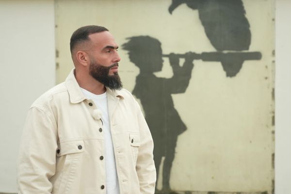 Le rappeur Médine devant une œuvre de Banksy, sur la plage de Calais, face à la Manche, le 16 novembre 2022.