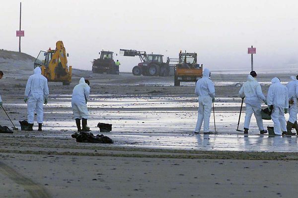 des employés municipaux de Biscarosse nettoient la plage centrale de la ville le 04 janvier 2003, après l'arrivée de milliers de boulettes d'hydrocarbures sur des dizaines de kilomètres de plage des Landes et de Gironde