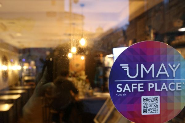 Un autocolllant de l'application UMAY SAFE PLACE apposé sur la vitrine d'un bar.