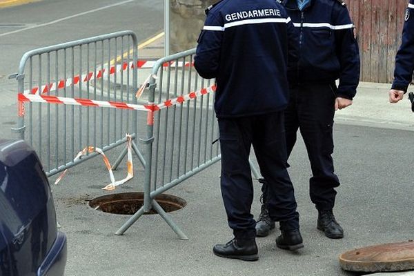 Des enquêteurs devant une bouche d'égout à quelques mètres de l'agence bancaire après la découverte du braquage