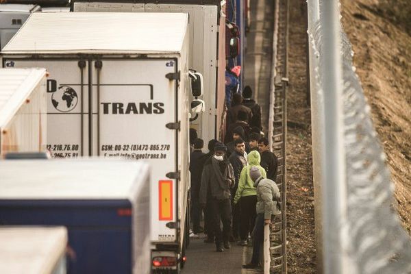 Des migrants sur la rocade portuaire de Calais tentant d'embarquer dans des camions.